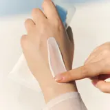 Applying Skin1004 Centella Sun Serum on back of hand - dewy no white cast